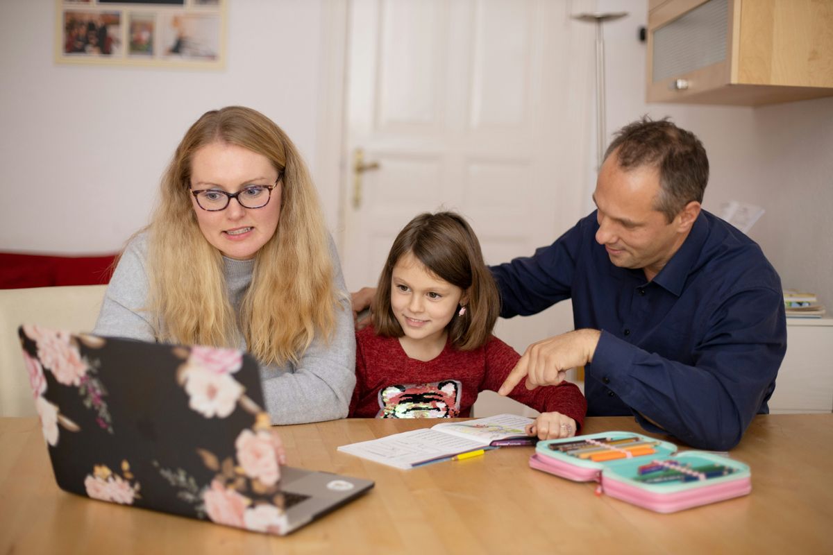 Eltern und Schülerin sitzen mit Laptop am Küchentisch
