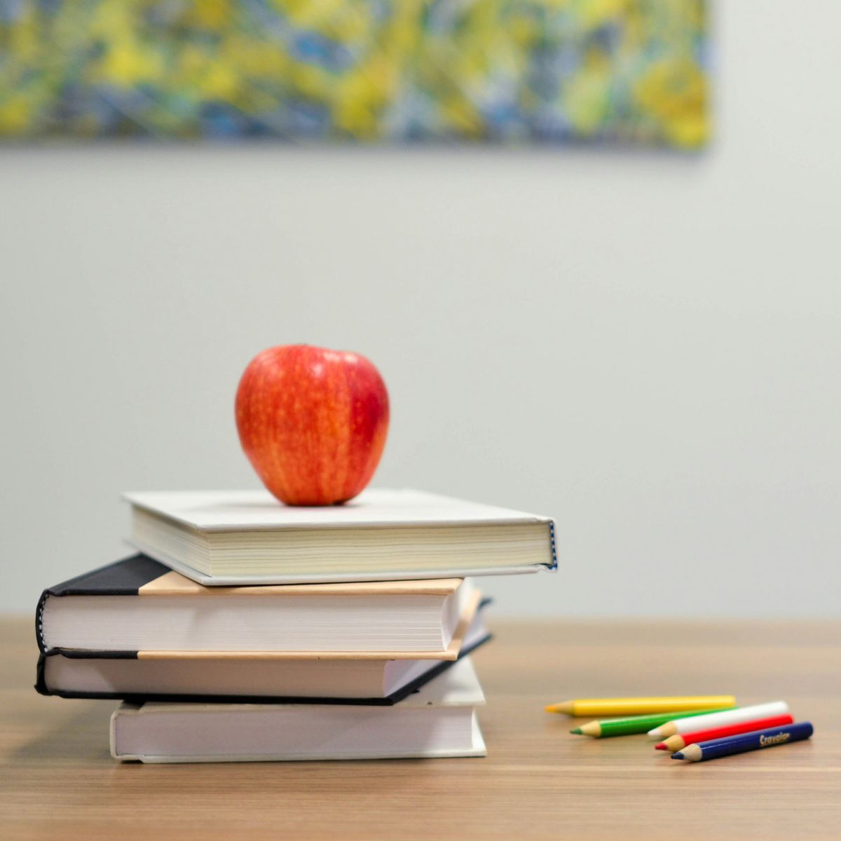Apfel liegt auf Büchern und Buntstifte daneben
